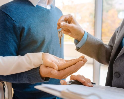 3 Hände Mann gibt Pärchen Schlüssel in die Hand